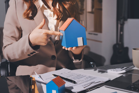 Female Real Estate Broker presenting and advised to 
model home and building project detail in the office, sign purchase sales contract, agreements concerned mortgage loan offer and insurance.の写真素材
