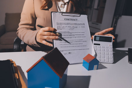 Female Real Estate Broker presenting and advised to 
model home and building project detail in the office, sign purchase sales contract, agreements concerned mortgage loan offer and insurance.の写真素材