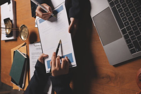 Attractive young lawyer in office Business woman and lawyers discussing contract papers with brass scale on wooden desk in office. Law, legal services, advice, Justice and real estate concept.の写真素材