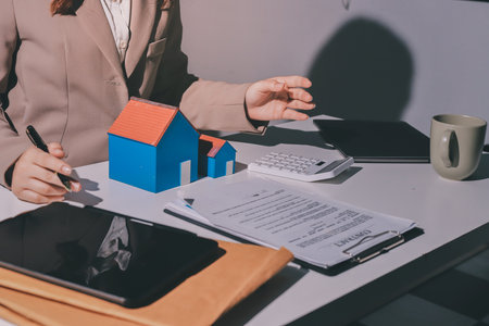 Female Real Estate Broker presenting and advised to model home and building project detail in the office, sign purchase sales contract, agreements concerned mortgage loan offer and insurance.の写真素材