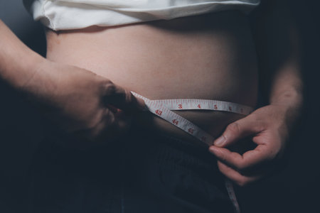 Asian man in front of a mirror looks at his body. Excess belly fat, Diet concept.