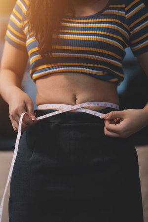 Cropped shot of woman touching and squeezing her belly.の写真素材