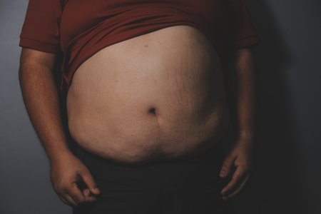 Fat man in front of a mirror looks at his body. Excess belly fat, Unhealthy lifestyle, Diet concept.