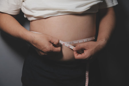 Asian man in front of a mirror looks at his body. Excess belly fat, Diet concept.の写真素材