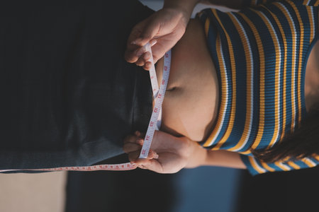 Cropped shot of woman touching and squeezing her belly.