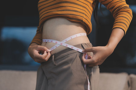 Cropped shot of woman touching and squeezing her belly.の写真素材