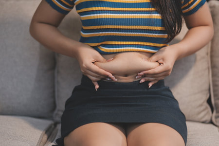 Cropped shot of woman touching and squeezing her belly.