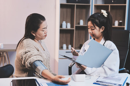 Doctor using sphygmomanometer with stethoscope checking blood pressure to a patient in the hospital.の写真素材