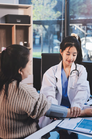 Doctor using sphygmomanometer with stethoscope checking blood pressure to a patient in the hospital.の写真素材