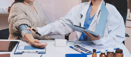 Doctor using sphygmomanometer with stethoscope checking blood pressure to a patient in the hospital.