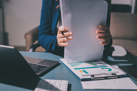 Expert woman asian female people review data number costing managerial account prepare monthly actual cost variance report at tax audit office. ESG sheet budget control ERP process service project.の写真素材