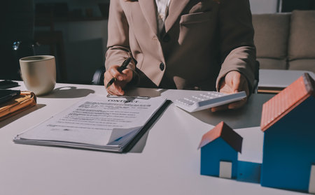Female Real Estate Broker presenting and advised to 
model home and building project detail in the office, sign purchase sales contract, agreements concerned mortgage loan offer and insurance.の写真素材