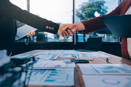 Young businessman shaking hands with businesswoman at officeの写真素材