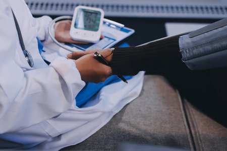 Doctor using Blood pressure monitor and stethoscope checking measuring arterial blood pressure on arm to a patient in the hospital, healthcare and medical conceptの写真素材
