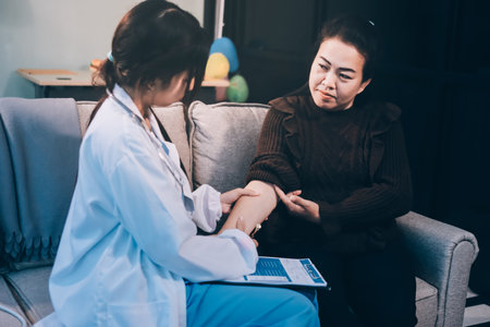 Homecare nursing service and elderly people cardiology healthcare. Close up of young hispanic female doctor nurse check mature caucasian man patient heartbeat using stethoscope during visitの写真素材