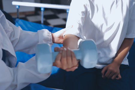 Unrecognizable uses blue hand weight during physical therapy sessionの写真素材