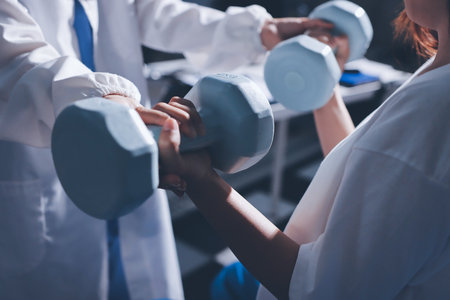 Unrecognizable uses blue hand weight during physical therapy sessionの写真素材