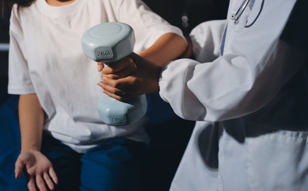 Unrecognizable uses blue hand weight during physical therapy sessionの写真素材