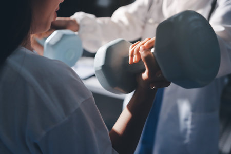 Unrecognizable uses blue hand weight during physical therapy sessionの写真素材