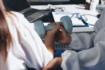 Unrecognizable uses blue hand weight during physical therapy sessionの写真素材