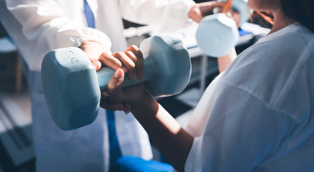 Unrecognizable uses blue hand weight during physical therapy sessionの写真素材