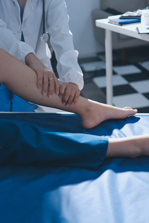 Female doctor hands doing physical therapy By extending the leg and knee of a male patientの写真素材