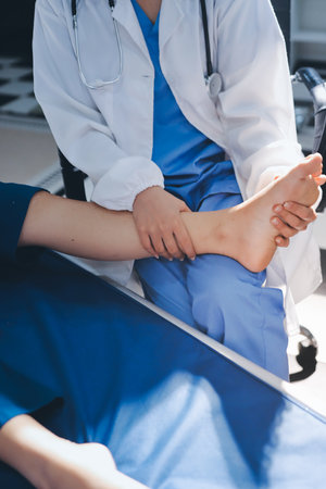 Female doctor hands doing physical therapy By extending the leg and knee of a male patientの写真素材