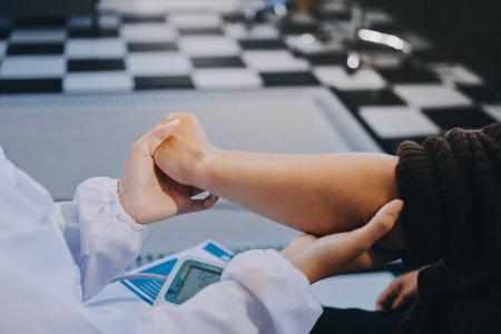 Orthopaedic doctor doing physical examination patient with wrist pain at the clinic. Physical therapist checks the patient wrist by pressing the wrist bone.の写真素材