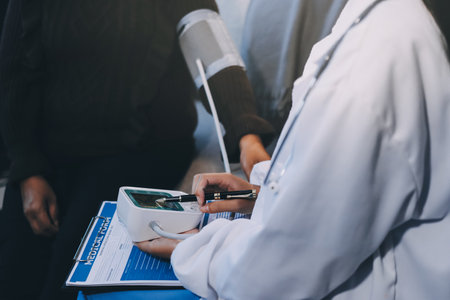 Doctor using Blood pressure monitor and stethoscope checking measuring arterial blood pressure on arm to a patient in the hospital, healthcare and medical conceptの写真素材