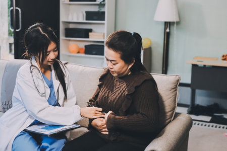 Homecare nursing service and elderly people cardiology healthcare. Close up of young asian female doctor nurse check mature asian woman patient heartbeat using stethoscope during visitの写真素材