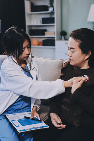 Homecare nursing service and elderly people cardiology healthcare. Close up of young female doctor nurse check mature woman patient heartbeat using stethoscope during visitの写真素材