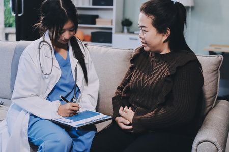 Homecare nursing service and elderly people cardiology healthcare. Close up of young hispanic female doctor nurse check mature caucasian man patient heartbeat using stethoscope during visitの写真素材