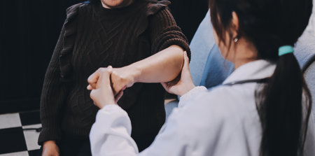 Orthopaedic doctor doing physical examination patient with wrist pain at the clinic. Physical therapist checks the patient wrist by pressing the wrist bone.の写真素材