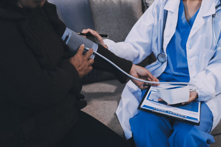 Doctor using Blood pressure monitor and stethoscope checking measuring arterial blood pressure on arm to a patient in the hospital, healthcare and medical conceptの写真素材