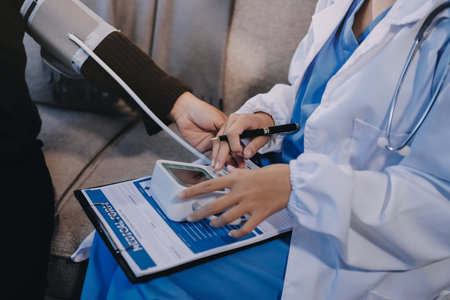 Doctor using Blood pressure monitor and stethoscope checking measuring arterial blood pressure on arm to a patient in the hospital, healthcare and medical conceptの写真素材