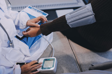 Doctor using Blood pressure monitor and stethoscope checking measuring arterial blood pressure on arm to a patient in the hospital, healthcare and medical conceptの写真素材