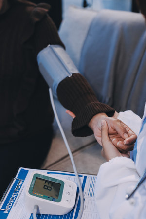 Doctor using Blood pressure monitor and stethoscope checking measuring arterial blood pressure on arm to a patient in the hospital, healthcare and medical conceptの写真素材