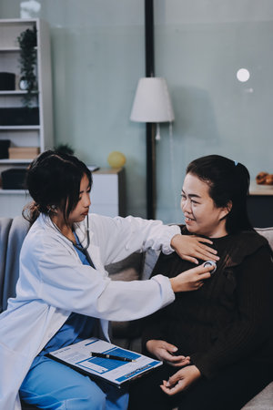 Homecare nursing service and elderly people cardiology healthcare. Close up of young female doctor nurse check mature female patient heartbeat using stethoscope during visitの写真素材