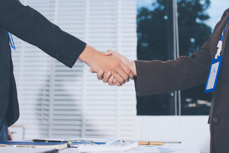 Two businessmen shaking hands after reaching agreement in officeの写真素材