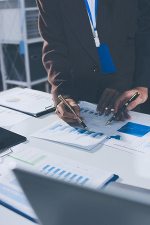Focused young businessman signing agreement with skilled lawyer in eyeglasses. Concentrated financial advisor showing place for signature on paper contract document to male client at meeting in officeの写真素材