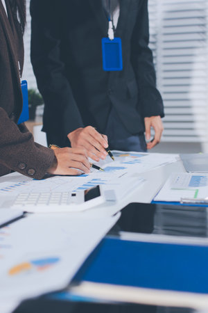 Focused young businessman signing agreement with skilled lawyer in eyeglasses. Concentrated financial advisor showing place for signature on paper contract document to male client at meeting in officeの写真素材