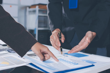 Focused young businessman signing agreement with skilled lawyer in eyeglasses. Concentrated financial advisor showing place for signature on paper contract document to male client at meeting in officeの写真素材