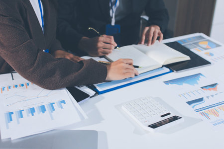 Focused young businessman signing agreement with skilled lawyer in eyeglasses. Concentrated financial advisor showing place for signature on paper contract document to male client at meeting in officeの写真素材
