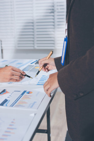 Focused young businessman signing agreement with skilled lawyer in eyeglasses. Concentrated financial advisor showing place for signature on paper contract document to male client at meeting in officeの写真素材