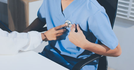 A physician uses a stethoscope to examine a patient's heart during a clinic appointment.の写真素材