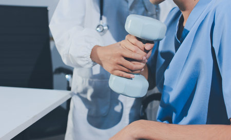 Person using hand weight with support of nurseの写真素材