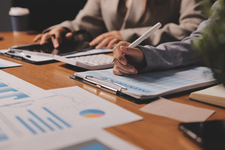 Group of confident business people point to graphs and charts to analyze market data, balance sheet, account, net profit to plan new sales strategies to increase production capacity.の写真素材