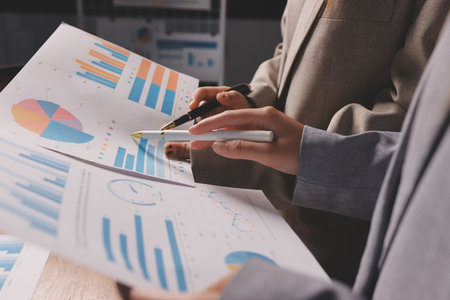 Group of confident business people point to graphs and charts to analyze market data, balance sheet, account, net profit to plan new sales strategies to increase production capacity.の写真素材