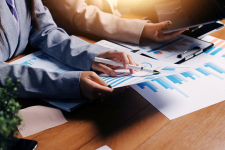 Group of confident business people point to graphs and charts to analyze market data, balance sheet, account, net profit to plan new sales strategies to increase production capacity.の写真素材