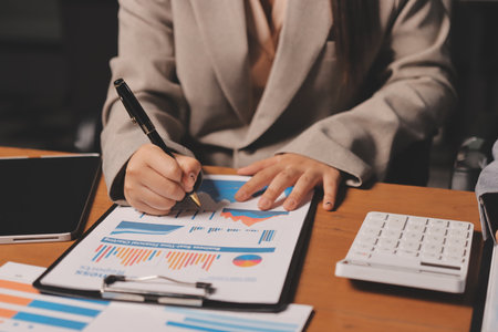 Group of confident business people point to graphs and charts to analyze market data, balance sheet, account, net profit to plan new sales strategies to increase production capacity.の写真素材